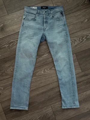 Replay Grover ljusblå jeans straight fit - Säljer ett par Replay Grover jeans i ljusblå tvätt med straight fit. Klassisk femficksmodell med Replay-logga på fickan och läderpatch bak i midjan. Jeansen är tillverkade i mjukt denimtyg och har normal midja. Perfekta för en avslappnad och stilren look. De har en liten reva där bak på vänster ben som man ser på sista bilden 