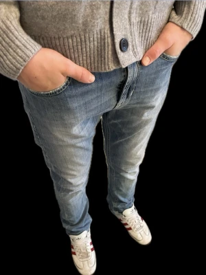 Blå dondup jeans! - Säljer ett par snygga blå jeans från dondup med klassisk femficksdesign och diskret dondup-logga på bakfickan. Jeansen har en tapered passform och är tillverkade i mjukt denim-material med lätt slitning för en cool look.