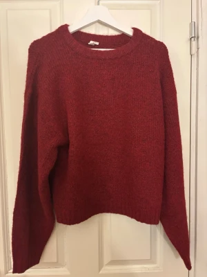 Vinröd stickad tröja från Nelly - Mysig vinröd stickad tröja från Nelly i fuzzy material. Tröjan har en rund halsringning och långa ärmar med relaxed fit. Perfekt för kalla dagar och enkel att styla med jeans eller kjol. Helt oanvänd endast testad på en gång. Påse till tröjan medkommer.