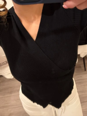 Svart omlottopp i ribbad material - Kramar om kroppen jättefint. Använt ett par gånger 