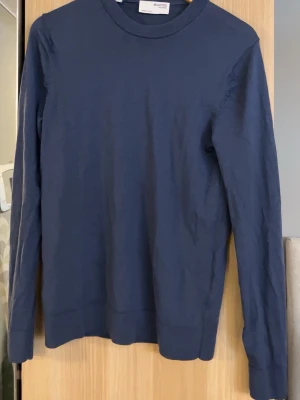 Mörkblå merinoulltröja från Selected Homme - Snygg mörkblå tröja från Selected Homme i mjuk merinoull. Klassisk rund halsringning och långärmad modell med ribbade muddar. Perfekt för dig som gillar stilrena och enkla plagg med skön passform.