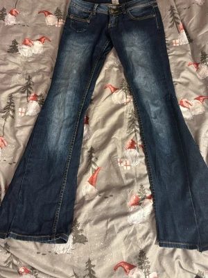 Blå bootcut jeans  - Säljer ett par mörkblå bootcut jeans med snygga slitningar och kontrastsömmar. Klassisk femficksmodell och låg midja. Jeansen är i kraftigt denimtyg och har coola detaljer på bakfickorna. Perfekta för dig som gillar retrovibbar och breda ben. Dessa jeans är omsydda ifrån skinny byxor till bootcut.🩷Byxorna står det ingen storleks lapp men de passar mig väldigt bra som är 167cm lång.