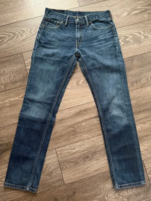 Levi's 511 blå jeans W30 L32 - Säljer ett par Levi's 511 jeans i klassisk blå tvätt med smal passform. Jeansen har fem fickor, snygga kontrastsömmar och den ikoniska Levi's-lappen bak i midjan. Perfekt för dig som gillar en modern och stilren look. Fri frakt