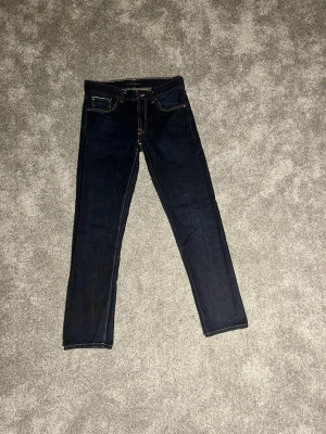 🇯🇵Japanska salvage gritty Jackson nudie jeans - Säljer ett par mörkblå  jeans från Nudie Jeans med klassisk femficksdesign och kontrastsömmar. Jeansen har en snygg, smal passform och är tillverkade i slitstarkt jeansmaterial. Perfekta till sneakers eller boots för en clean look.