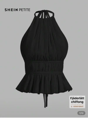 Svart chiffong halterneck topp Shein - Säljer en svart halterneck topp från Shein i fjäderlätt chiffong. Toppen har volangkant nedtill, smockad midja och 1 knytband i nacken och 2 i ryggen. Öppen rygg och figurnära passform som ger en snygg siluett. Perfekt till jeans eller kjol. Storleken står att det är ”Petite S” men skulle gissa på att det är i princip samma sak som XS. Säljes då jag endast använt den en gång och nu ligger den bara i garderoben och tar upp plats. 