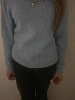 Ljusblå fluffig stickad tröja - Mysig ljusblå stickad tröja med fluffig känsla. Tröjan har rund halsringning och långa ärmar, perfekt för kyligare dagar. Enkel och stilren design som är lätt att matcha med olika outfits. Storlek xs-s skulle jag uppskatta lappen är borta. 
