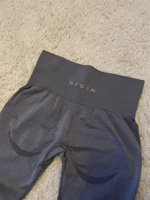 Snygga NVGTN tights - Snygga grå NVGTN tights i stl S. Har liten ”reva” som syns på sista bilden och till vänster på andra bilden. Sitter snyggt på och har en skugg effekt under rumpan. 