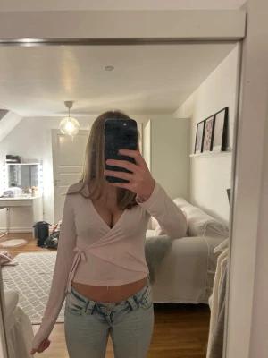 Ljusrosa omlottopp från Gina Tricot - Supersöt ljusrosa topp från Gina Tricot med långa ärmar och knyt i sidan. Toppen har en croppad passform och en v-ringningt. Perfekt att styla med jeans, finns en super liten fläck längst ner vid handleden som går bort i tvätten (toppen tvättas självklart innan jag skickar den) 💕skriv om ni har frågor och priset är diskuterbart 💕