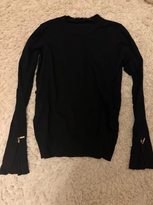 Svart finstickad tröja med kedjor - Jag säljer en finstickad tröja från Zara med en tajt passform i midjan och lite lösare över bröstet. Den har kedjor i ärmarna som en extra detalj. 