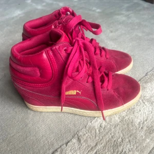 Rosa kilklack sneakers puma  - Sjukt snygga rosa  sneakers med kilklack från Puma. Skorna är en gammal model som inte säljs längre. Det är använda men fortfarande i ett gott skick. Mycket bekväma att gå i trots klacken.                   Skriv vid fler frågor 💕