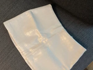 Vit kort kjol från H&M DIVIDED - Säljer en vit kort kjol från H&M DIVIDED i storlek 38. Kjolen har en glansig yta med croco-präglat mönster och en snygg dragkedja i sidan. Materialet är syntet och polyester, vilket ger en cool och modern look. Perfekt för dig som gillar trendiga detaljer.