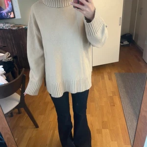 Beige polotröja från H&M - Säljer en beige polotröja från H&M i storlek S. Tröjan är stickad med grov ribbad kant vid hals, ärmslut och nederkant. Den har en oversized passform och långa ärmar, perfekt för att hålla sig varm och snygg under kyliga dagar.