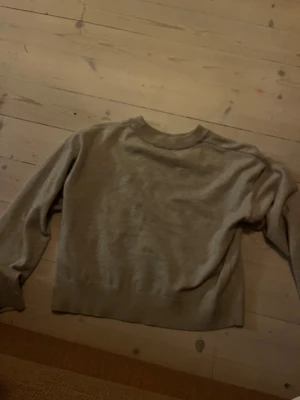 Beige tröja med AMORE från Gina Tricot - Beige polotröja från Gina Tricot med svart text 'AMORE' framtill. Tröjan har lång ärm, ribbade muddar och en mjuk, stickad känsla. Perfekt för dig som gillar enkel stil med en cool detalj framtill.