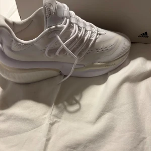 Adidas AlphaBounce V1 vita sneakers - Säljer ett par Adidas AlphaBounce V1 sneakers i helvitt. Skorna har aldrig använts. Köptes länge sedan på Intersport , ganska säker på att Adidas inte producerar dessa längre. Stl 41 1/3. Original förpackning och ”tags” kvar.                                                       Adidas beskrivning av skorna: Skorna har ventilerande mesh, snörning och en chunky sula med Adiprene och Bounce-teknologi för extra komfort. Perfekt för dig som gillar sportig stil och vill ha något fräscht på fötterna.