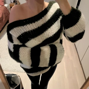 Randig stickad tröja Design by Si - Säljer en oversized stickad tröja från Design by Si med breda mörk gröna och vita ränder. Tröjan har en loose passform, långärmade ärmar och en bred halsringning som kan bäras offshoulder. 