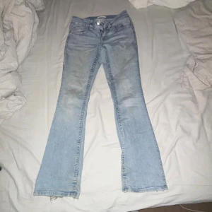 Ljusblå bootcut jeans från Levi's - Säljer ett par ljusblå Levi's jeans med klassisk bootcut passform. Jeansen har fem fickor, knapp och dragkedja framtill samt slitna detaljer vid bensluten. Perfekt för dig som gillar retrovibe och relaxed stil.