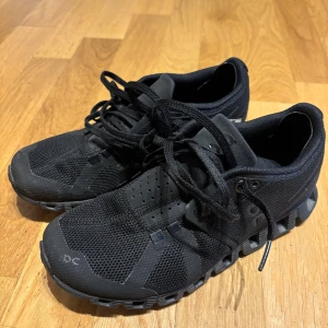 Svarta On Running sneakers W5.5 - Svarta On Running sneakers med cool mesh-överdel och sportig design. Skorna har snörning, platt sula och rund tå. Märket syns tydligt på sidan och innersulan. Perfekta för dig som gillar stilrena och funktionella träningsskor. Strlk 36,5