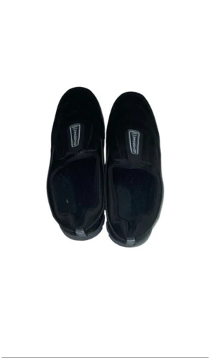 Svarta outdoor loafers med grov sula - Svarta loafers från Outdoor med grov, mönstrad sula för extra grepp. Skorna har en rund tå och är tillverkade i mocka med syntetdetaljer. Enkla att ta på tack vare den breda öppningen och stilren design med svart färg och diskret logga på ovansidan.