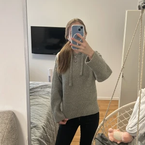 Grå stickad hoodie från Zara - Mysig grå stickad hoodie från Zara med huva och snörning. Tröjan har breda ribbade muddar vid ärmslut och nederkant, samt en loose passform. köpt för kanske 450kr pris kan diskuteras!