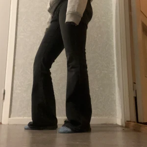 Svarta bootcut jeans - Säljer ett par svarta bootcut jeans med dragkedja. Jeansen har en snygg utsvängd passform nertill och är tillverkade i ett mjukt denimtyg som sitter skönt på kroppen. Perfekta för dig som gillar en retroinspirerad look.