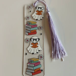 Halloween bokmärke  - Det här är ett bokmärke med ett gulligt spöktema! Perfekt för dig som älskar att läsa och vill ha något unikt och roligt i din bok. Spöket med glasögon och böcker ger en nördig och charmig känsla. Passar perfekt för den som älskar böcker.