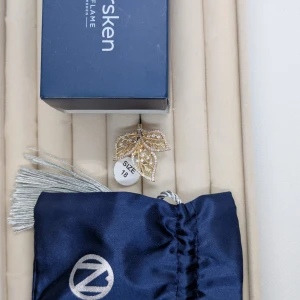 Guldring med glittriga löv från Oriflame - Unik guldfärgad ring från Oriflame med tre detaljerade löv dekorerade med små glittrande stenar. Ringen har en elegant och iögonfallande design som verkligen sticker ut. Perfekt för dig som gillar smycken med naturinspirerade former och extra bling.