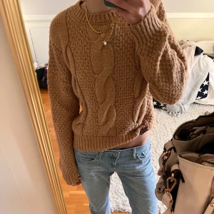 Skön stickad kabeltröja - Säljer en riktigt fin och skön beige stickad tröja med grovt kabelstickat mönster framtill. Tröjan har rund halsringning, långa ärmar och breda muddar. Perfekt för lager-på-lager och riktigt cozy vibes. Inte alls stickig 
