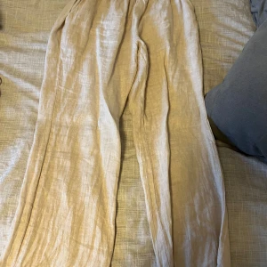 Beige linnebyxor från Chelsea Girls - Säljer ett par luftiga och sköna linnebyxor från Chelsea Girls i beige färg. Byxorna har en bred resår i midjan för extra komfort och en avslappnad passform med raka ben. Perfekta för varma dagar och chill stil. Skulle gissa att storleken är S för de passar mig som är 162.