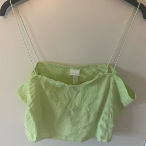 Ljusgrön ribbad linnetopp H&M - Säljer en ljusgrön ribbad linnetopp från H&M med tunna axelband. Toppen är croppad och har en mjuk, stretchig känsla. Perfekt för varma dagar och enkel att styla med jeans eller kjol.