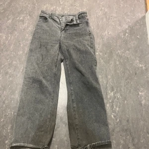 Gråa wide jeans  - Säljer ett par gråa jeans med bred passform , fransiga kanter nertill. Jeansen har en mitt midja . Perfekta för dig som gillar en avslappnad och trendig look.