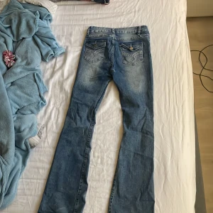 Blå bootcut jeans med detaljer - Blå bootcut jeans som e jätte bekväma!! Men finns tyvärr hål i mitten, men enkelt att sy till om man är kreativ, eller göra kjol till! Kom gärna med bud🩷