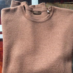 Brun stickad tröja från Stensröms  - En stilren brun stickad tröja från Stenströms med rund halsringning och lång ärm. Tröjan har en enkel och clean design utan mönster eller detaljer, perfekt för dig som gillar en klassisk look. Materialet känns mjukt och passar bra till lager-på-lager under höst och vinter.