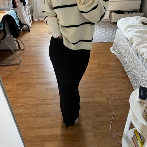 Kjol från Nelly - Säljer en svart långkjol med smal passform som sitter snyggt över höfterna och faller rakt ner mot golvet. Kjolen är enkel och stilren, perfekt att matcha med en stickad tröja eller t-shirt. Kjolen är från Nelly o är i storlek Xs 