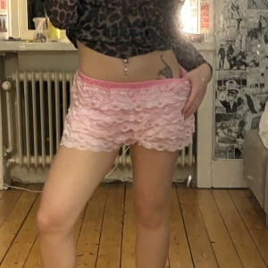 Rosa volangshorts i spets - Supersöta rosa shorts med flera lager volangig spets och elastisk midja. De är riktigt mjuka och köpta i vintage butik i vietnam. passar xs-s