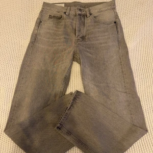 Grå raka jeans från Zara, strl 36 - Snygga grå jeans från Zara i rak modell med klassisk femficksdesign. Jeansen har normal passform och är tillverkade i bomull. Perfekta för dig som gillar en stilren och enkel look. Färgtonen är ljusgrå och materialet känns slitstarkt.