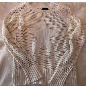 Vit stickad tröja med stjärna - Vit stickad tröja från Esprit med ett stort stjärnmönster framtill. Tröjan har långärmad design, grovstickat nätmönster och breda ribbade muddar vid ärmslut och nederkant. Perfekt för lager-på-lager under vår och sommar.