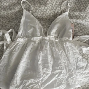 Vit linnetopp med rosetter på sidorna från Nelly💕 - Super söt sommar topp från Nelly💗helt oanvänd, med lappen kvar. 