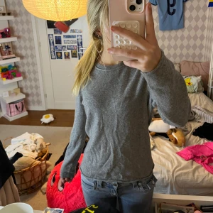 Grå kashmirtröja från BOSS - Supermjuk och stilren grå tröja från BOSS i 100% kashmir. Klassisk rund halsringning och långärmad modell som sitter snyggt och passar perfekt till jeans. Enkel och tidlös design som är lätt att matcha.