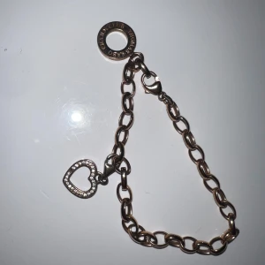 Thomas Sabo armband med hjärthänge rosé - Snyggt armband från Thomas Sabo i guldtonadrosé metall med grova länkar och ett glittrande hjärthänge dekorerat med små stenar. Saknas en sten. Perfekt accessoar för att lyfta din outfit med lite extra bling och kärleksfull vibe.19cm lång armband 