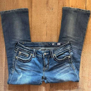 Blå jeans från Miss Me - Jättesnygga jeans från Miss Me. Dom är bootcut och lågmidjde. Dom saknar en knapp men inget man tänker på (se på sista bilden) 