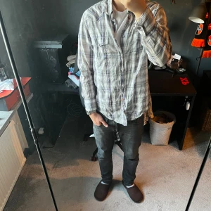 Hugo boss skjorta - Säljer en snygg rutig skjorta från Boss Orange i tunnt bomullstyg. Skjortan har blå, grå och beige toner, klassisk krage, bröstfickor med knappar och långa ärmar. Perfekt för dig som gillar en avslappnad men stilren look. Skriv för mer bilder