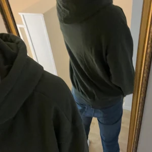 Olivgrön hoodie från H&M - Säljer en olivgrön hoodie från H&M i clean och relaxed fit. Tröjan har huva med snörning, magficka och långa ärmar. Perfekt för chill dagar och enkel att matcha med jeans eller joggers. Inga defekter. Passar även M. 