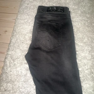 Replay svarta jeans med broderad patch - Snygga svarta jeans från Replay med en broderad patch bak och klassisk femficksdesign. Jeansen har en mörk tvätt och slim fitt, med Replay-logga på fickan. Perfekt för dig som gillar stilrena och coola jeans.