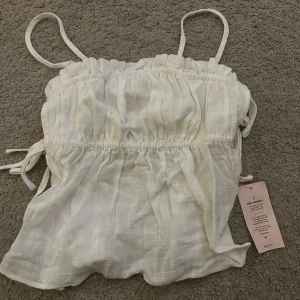 Topp i linnetyg  - Vit topp i linnetyg från Nelly, storlek 36. Oanvänd med lappen kvar