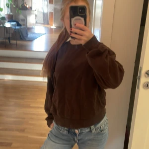 Brun manchestertröja med loose fit - Mysig brun tröja i manchester med avslappnad, loose passform och långa ärmar. Perfekt för dig som gillar en chill och trendig stil. Passar till jeans eller kjol för en enkel men snygg look.