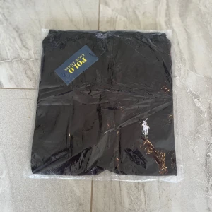 Svart t shirt S  från Polo Ralph Lauren - Svart t shirt från Polo Ralph Lauren med klassisk vit broderad logga på benet. Snygg och stilren design, perfekt för allt. Tillverkade i ett mjukt bomullsmaterial som känns skönt mot huden.