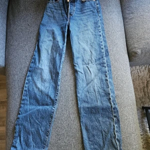 Levi's Ribcage Straight jeans blå - Säljer ett par Levi's Ribcage Straight jeans i klassisk blå denim. Hög midja, raka ben och snygga kontrastsömmar. Ikonisk läderpatch bak och röda Levi's-tag på bakfickan. Perfekta för dig som gillar vintagevibbar och tidlös stil. Inköpta för knappt ett år sedan, nypris 1299kr.