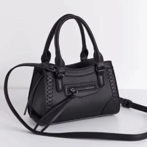 Svart handväska med dragkedja - Snygg svart handväska i skinnimitation med både handtag och avtagbar axelrem. Väskan har dekorativa sömmar på sidorna och en liten ficka med dragkedja framtill. Perfekt storlek för det viktigaste och stilren design som passar till många outfits.