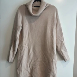 Beige stickad poloklänning  - Mysig beige stickad klänning från Mohito med polokrage och långa ärmar. Perfekt för kyliga dagar och enkel att styla med boots eller sneakers. Mjuk och skön känsla tack vare det stickade materialet. Kommer över knäna. 