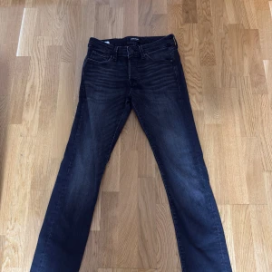 Mörkblå jeans från Jack & Jones - Snygga mörkblå jeans från Jack & Jones med klassisk femficksdesign och raka ben. Jeansen har en lätt tvättad look och är tillverkade i mjukt denimtyg med stretch för extra komfort. Perfekta för en avslappnad och stilren outfit.